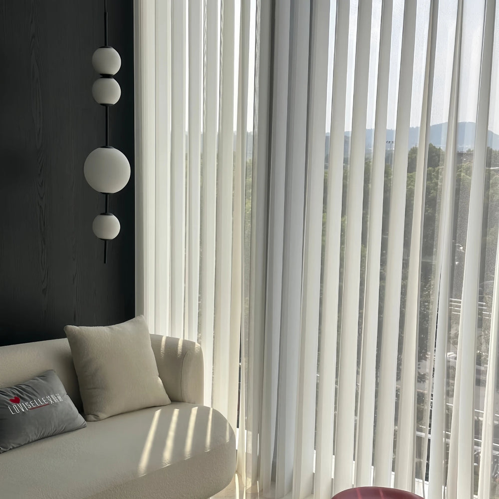 Modern interior with a sofa, decorative pillows, and a large window with vertical blinds.