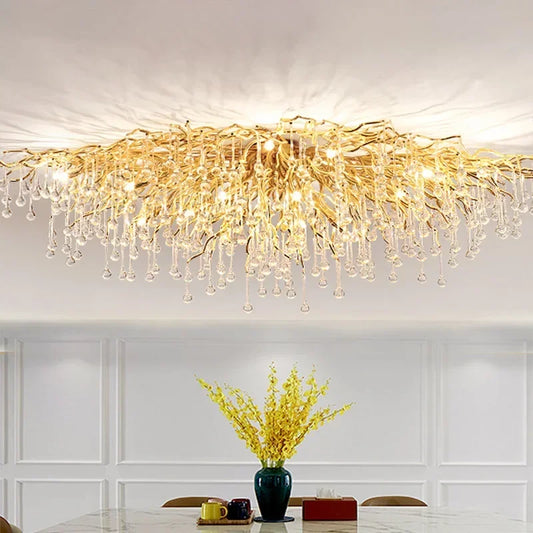 Gold crystal chandelier with cascading teardrop crystals hanging from a gold frame, mounted on a white ceiling.