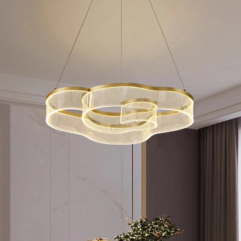 Modern chandelier hanging in a room with neutral walls and a plant.