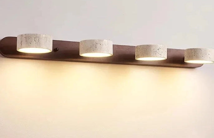 Modern wall-mounted light fixture with four cylindrical lights on a plain background