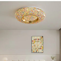 Circular flush mount ceiling light with a multi-colored textured surround and a central gold ring, studded with small colorful elements.