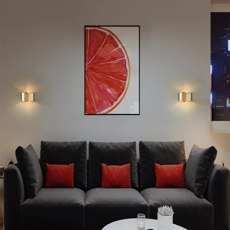 Modern living room with a gray sofa, red cushions, and a framed artwork of a pink grapefruit.