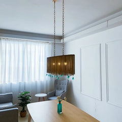 Wide shot of a gold chain chandelier with blue teardrop crystals in a dining area