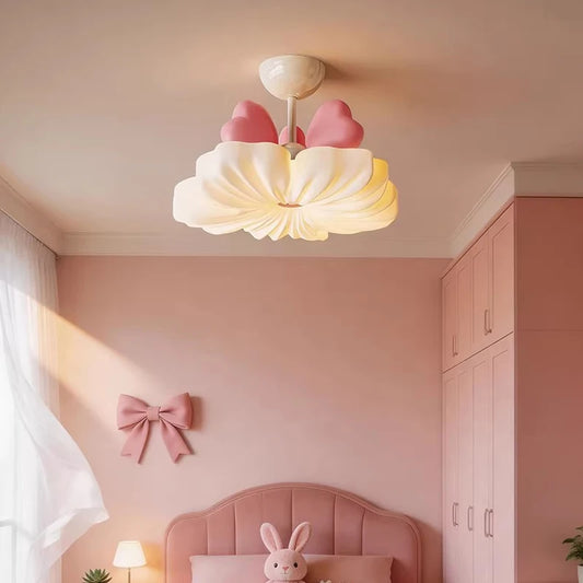 White flower cloud flush mount ceiling light with pink bow accents in a pink-themed child's bedroom.