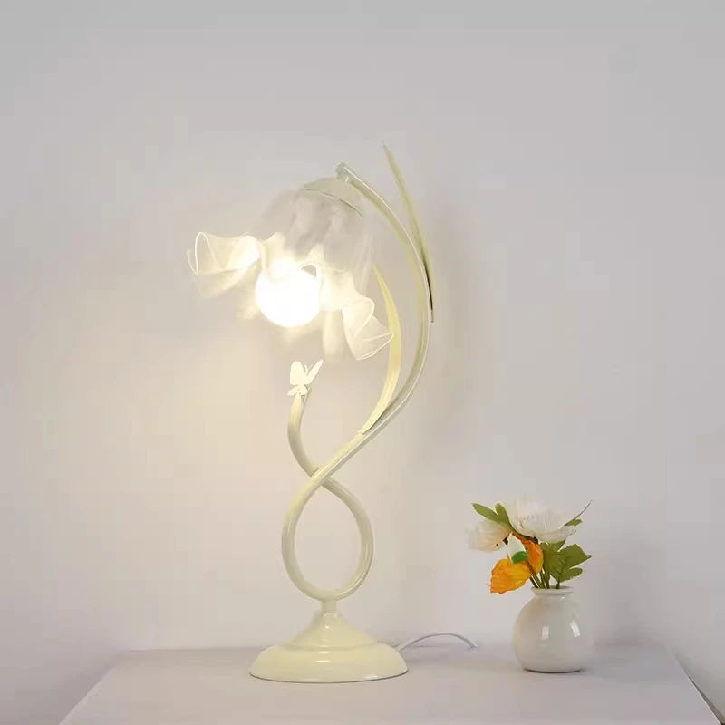 Decorative table lamp with a white base and glass shade on a light gray surface.