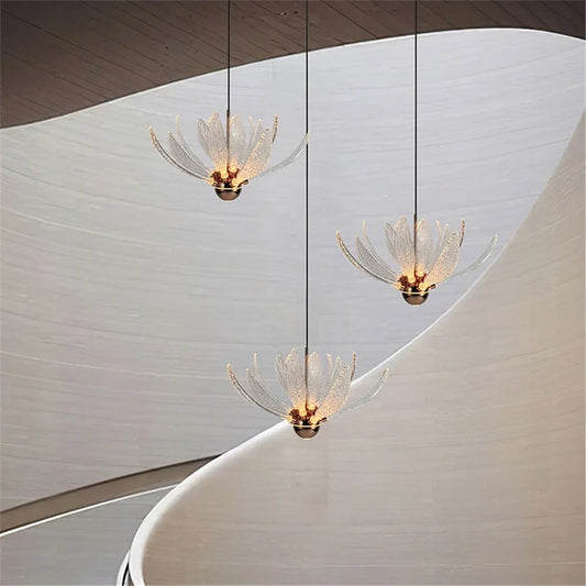 Three clear acrylic lotus flower pendant lights hanging from a ceiling in a modern interior with curved white walls.