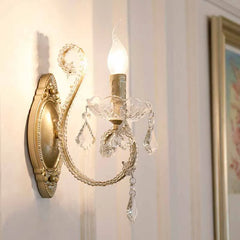 Close-up of a gold crystal candelabra style wall sconce with ornate detailing.