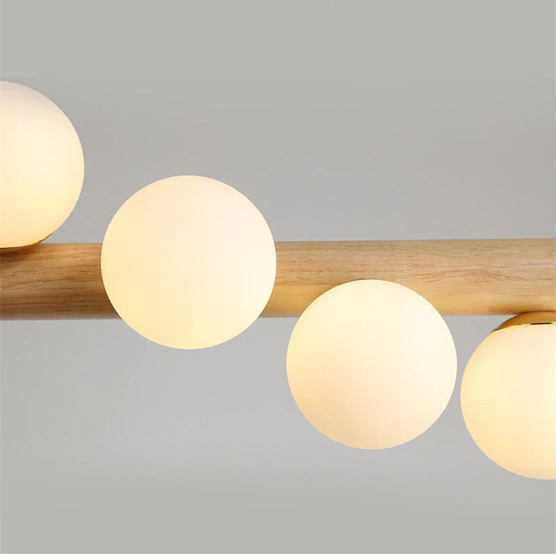 Ceiling light fixture with wooden bar and round glass shades on a gray background