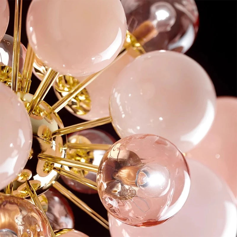 Close-up of a modern chandelier with pink and gold spherical lights.