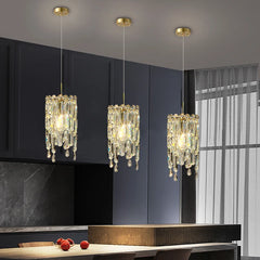 Three gold tiered crystal pendant lights hanging over a kitchen island