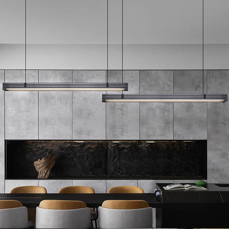 Modern kitchen with gray tiled walls, black marble backsplash, and wooden chairs.