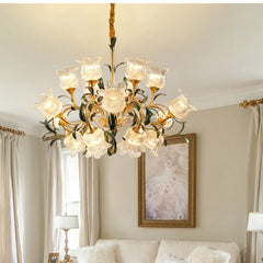 A multi-arm gold chandelier with clear glass floral shades is showcased in a well-decorated living room setting.