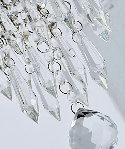 Close-up of a crystal chandelier with clear glass prisms on a light gray background