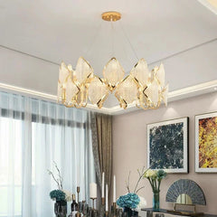 Gold tiered chandelier with clear crystal accents hanging above a dining table.