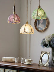 Three colorful pendant lights hanging above a wooden surface with decorative items.