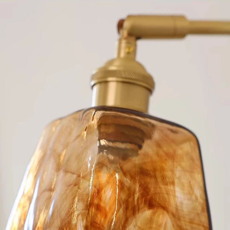 Gold-toned soap dispenser with a textured glass bottle on a plain background
