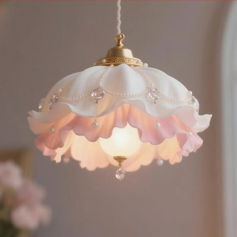 Close-up of a gold pendant light with pink and white floral petals adorned with pearls and crystals.