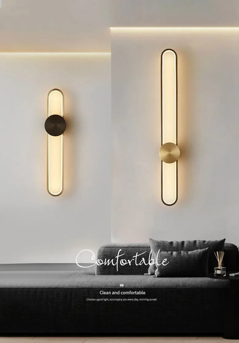 Modern wall lights on a white wall with a sofa and decorative items in the foreground.