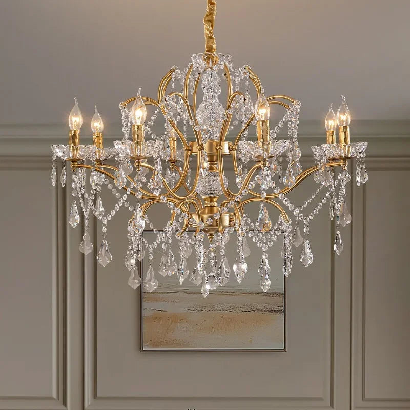 A wide shot of a gold crystal chandelier hanging above a framed artwork in a well-decorated room.