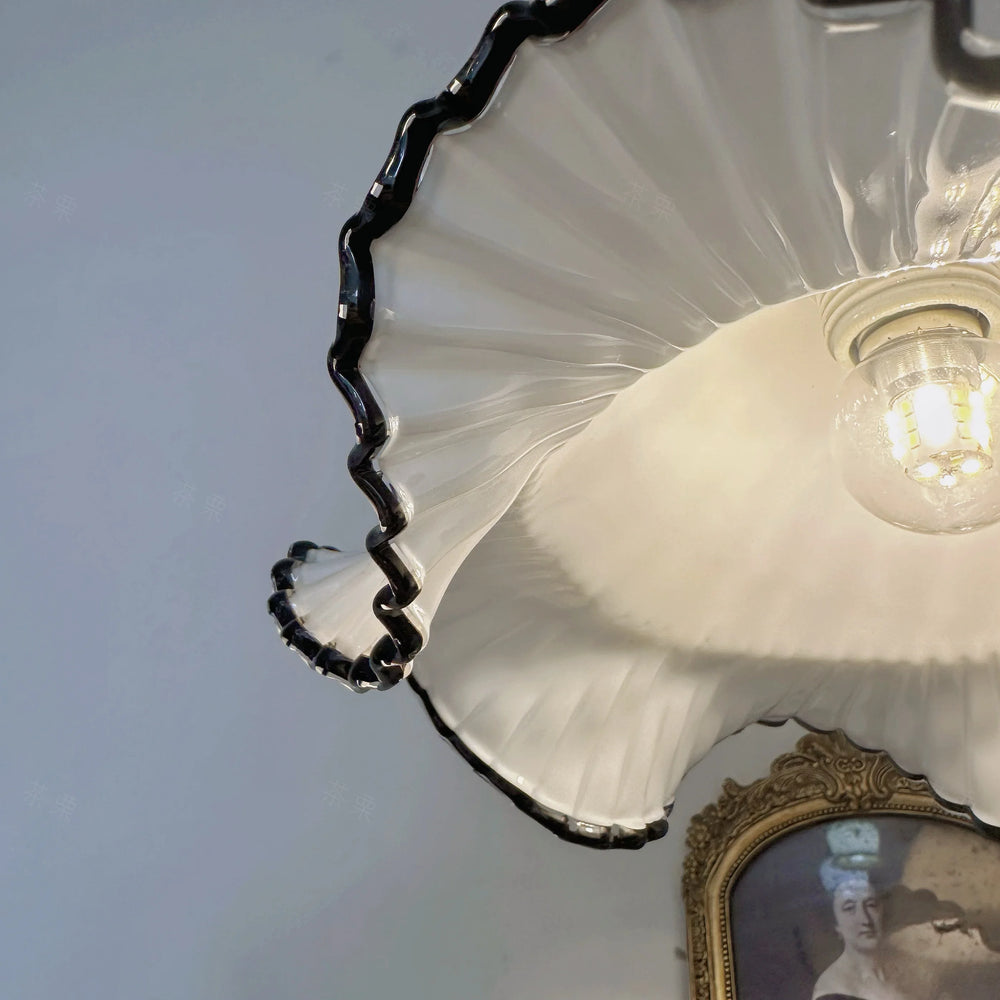 Ceiling light fixture with scalloped edge and visible bulb, against a plain wall.