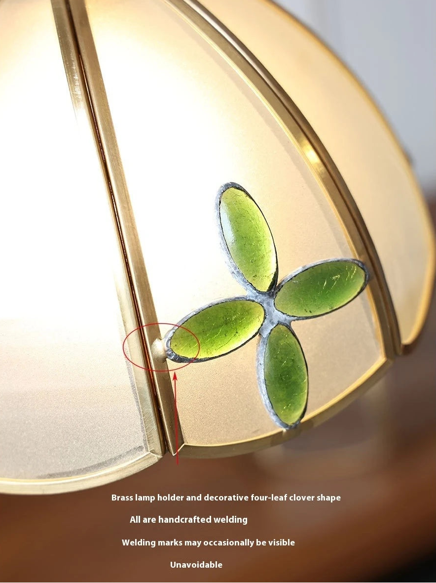 Decorative light fixture with a four-leaf clover design on a gold frame.
