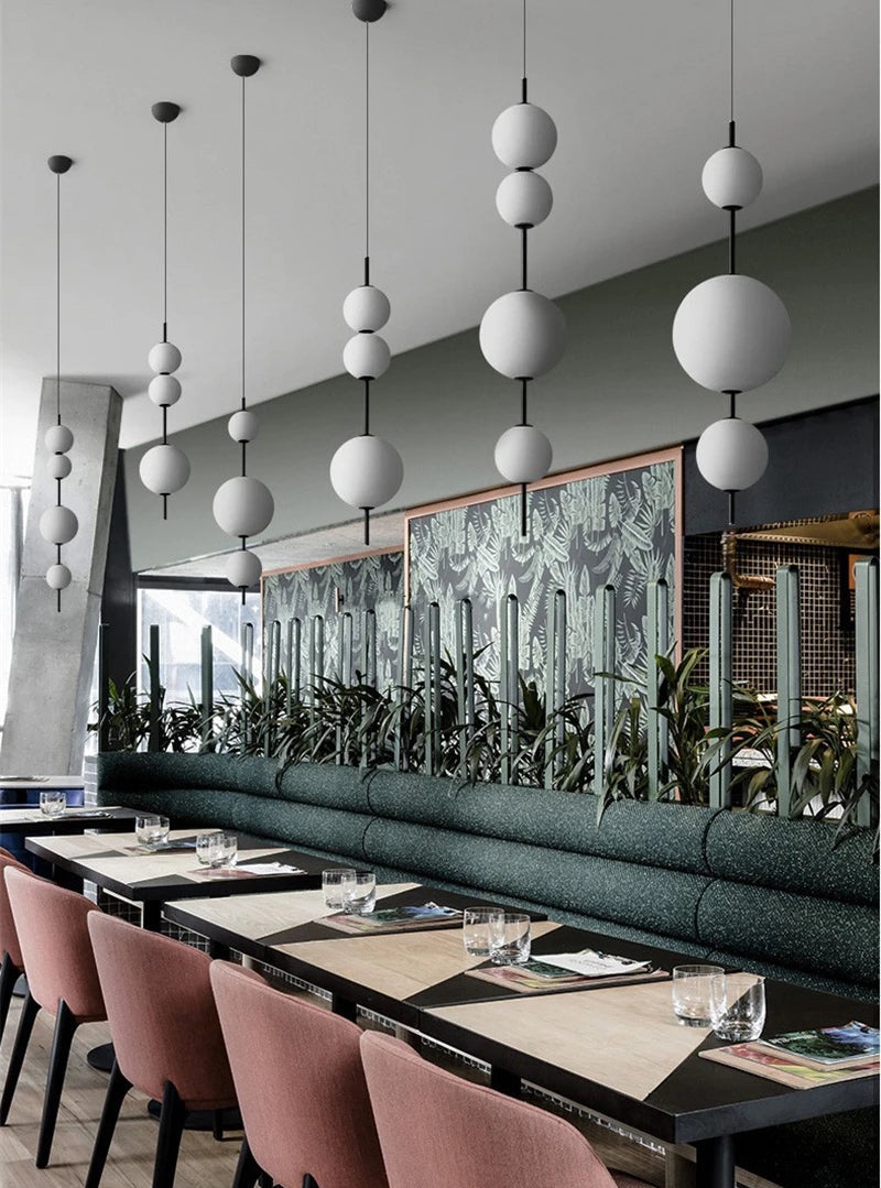 Modern restaurant interior with long dining table, pink chairs, and decorative wall art.