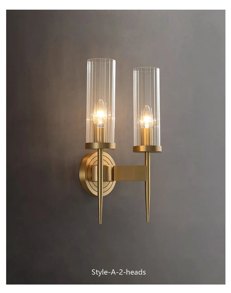 Gold wall sconce with two clear glass shades on a gray background