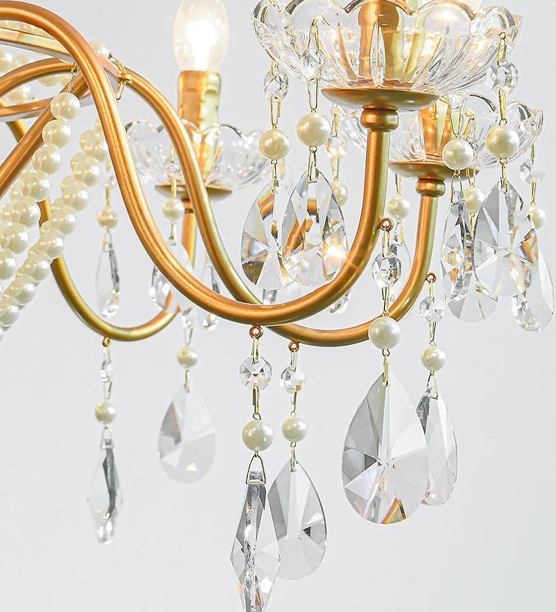 Gold chandelier with crystal and pearl accents on a light gray background