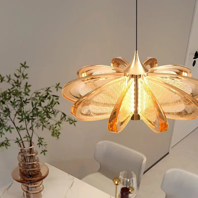 Gold floral pendant light fixture in a room with a vase and plant.