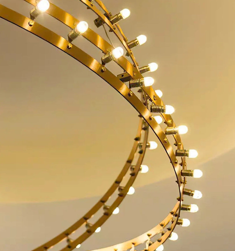 Gold circular light fixture with multiple bulbs on a neutral background