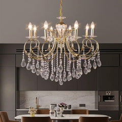 A gold candelabra crystal chandelier installed in a modern dining room setting above a table.