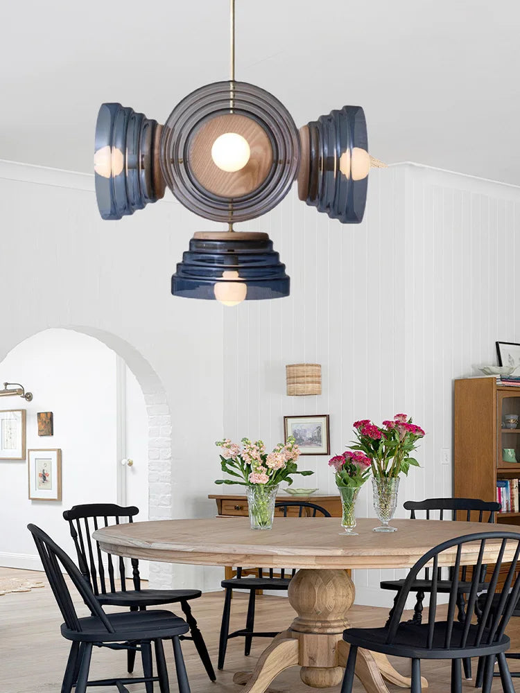 Modern pendant light fixture hanging above a dining table with black chairs in a bright room.
