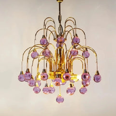 Close-up view of the gold metalwork and purple droplet crystals on a cascading chandelier.