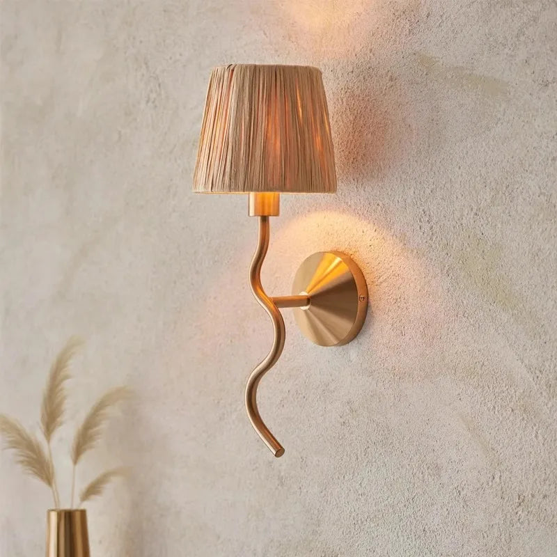 Gold wall sconce with a textured lampshade on a textured wall.