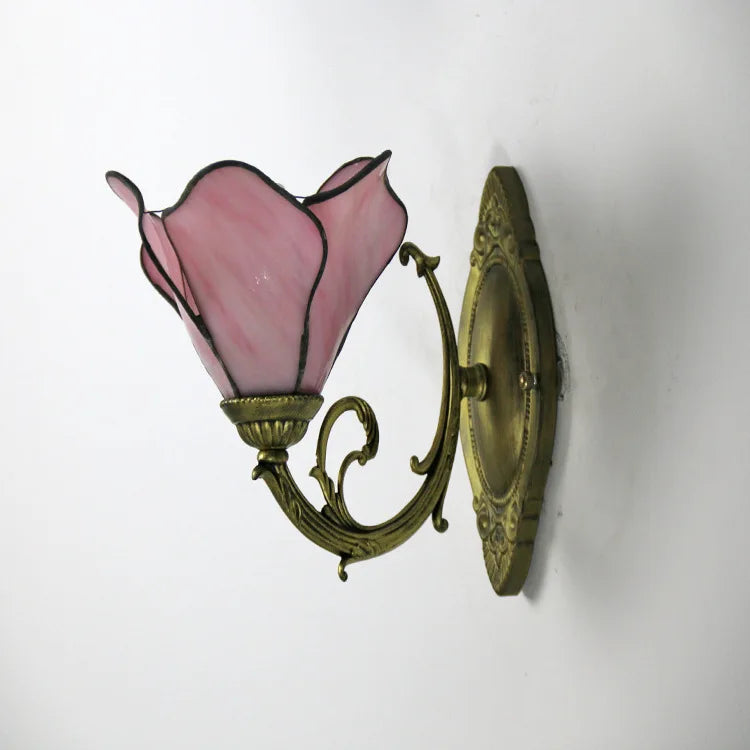Wall-mounted lamp with pink glass shade and gold metal fixture on a white background