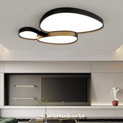 Black version of the cloud-shaped LED ceiling light installed in a modern living room with a television and fireplace.