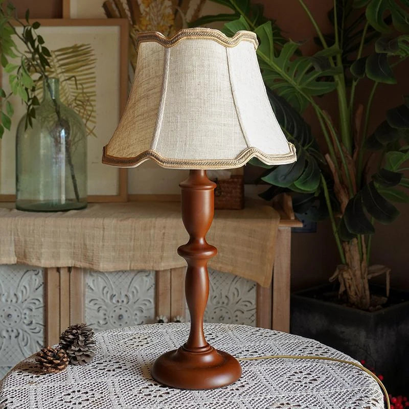 Decorative table lamp with a wooden base and white lampshade on a textured surface.