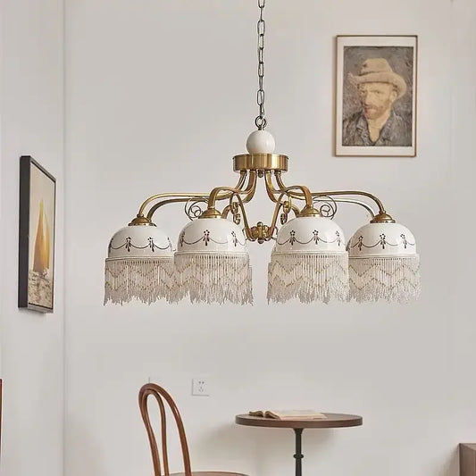 Close-up of the gold floral ceramic pendant light, showing detailed patterns and tassels.