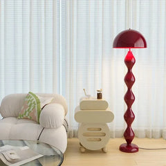 Red mushroom floor lamp with a segmented base in a room with a white chair.
