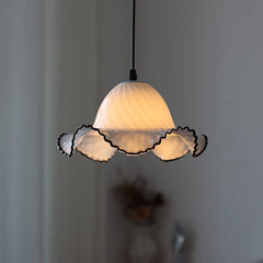 Close-up of a white glass fluted pendant light with a black trim, illuminated against a dark background.