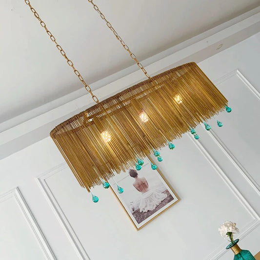 Close-up of a gold chain chandelier with blue teardrop crystals, angled view