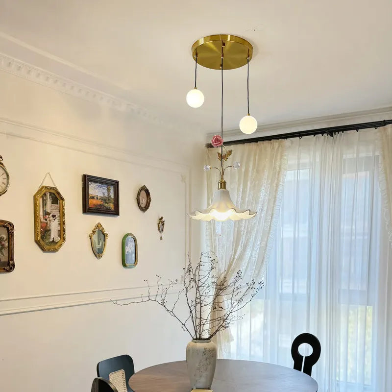 Dining room setting with a gold floral rose bud ceramic pendant light centered above a round table