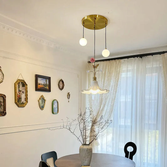 Dining room setting with a gold floral rose bud ceramic pendant light centered above a round table
