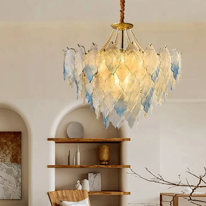 Decorative chandelier with feather-like design in a room with shelves and decor.