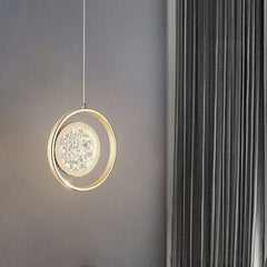A single gold ring pendant light with a crystal diffuser hanging in a room with grey curtains.