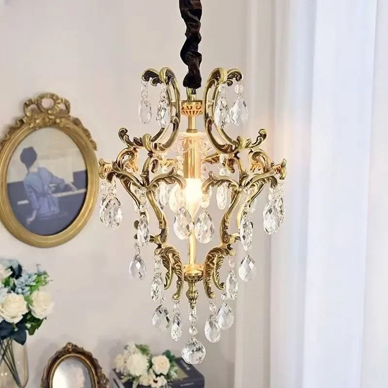 View of a gold crystal chandelier with a framed picture and flowers in the background.