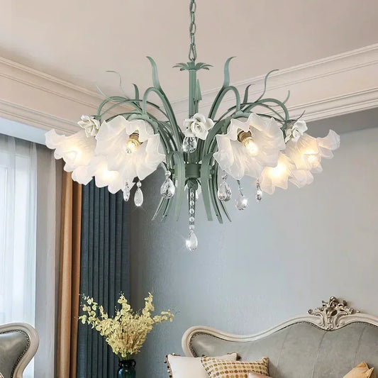 Green floral ceramic chandelier with crystal accents, hanging in a room with light gray walls and curtains.