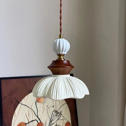 Cream-style bell-shaped pendant light with a ribbed resin shade and walnut accents, hanging against a neutral wall.