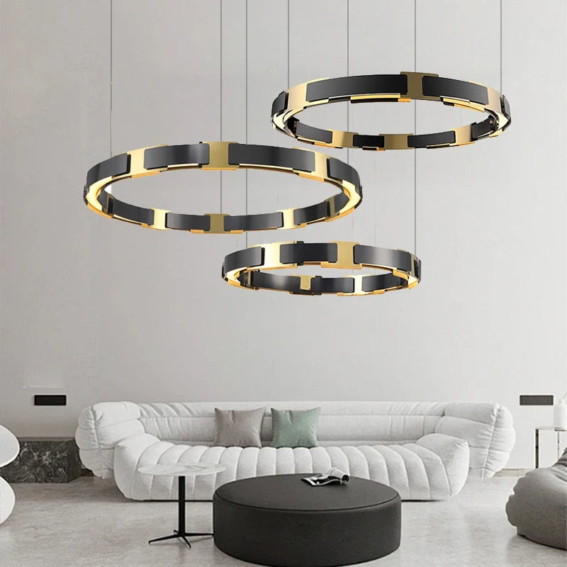 Modern living room with black and gold circular pendant lights, white sofa, and round ottoman.