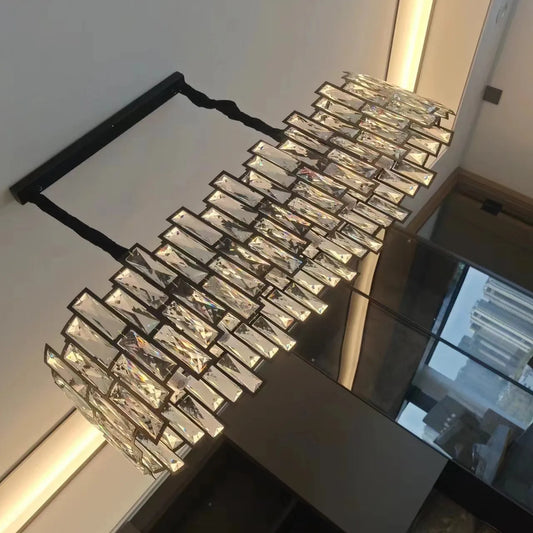 A contemporary chandelier with multiple tiers of clear, rectangular crystals attached to a black frame, hanging from a ceiling.